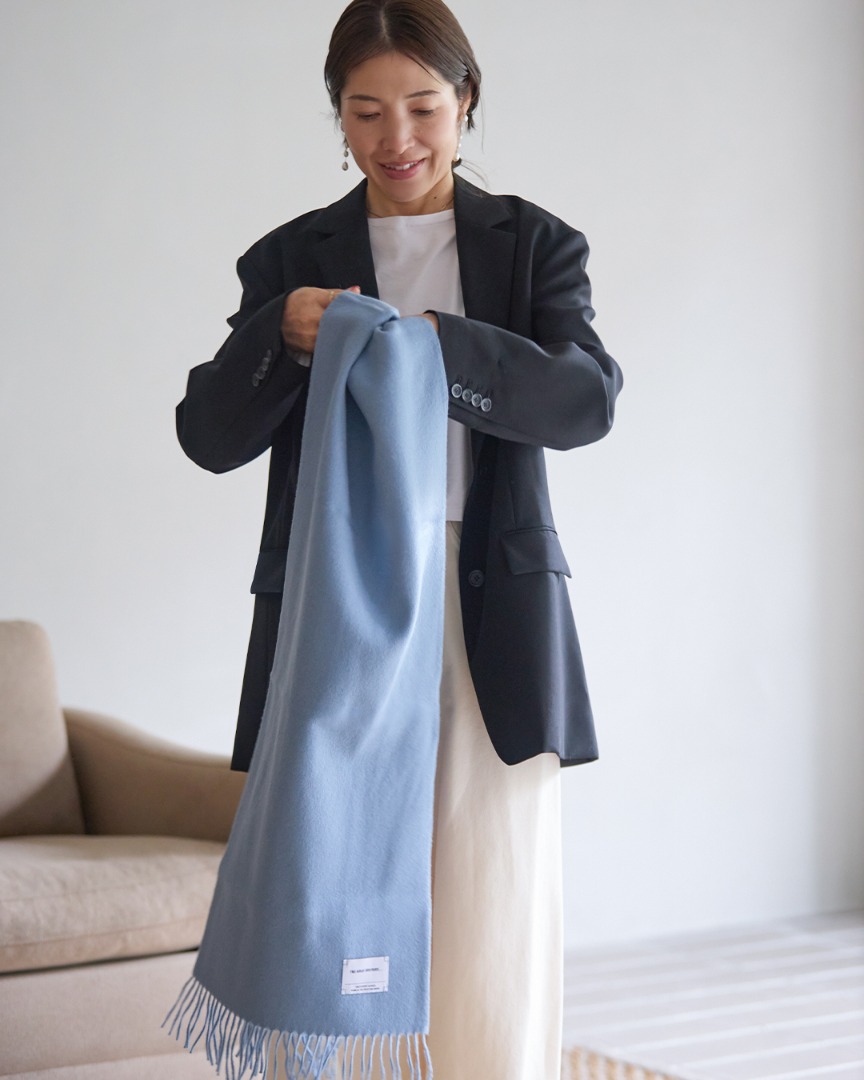 Accent Color Scarfを手に持ち、広げてサイズ感を見せている様子